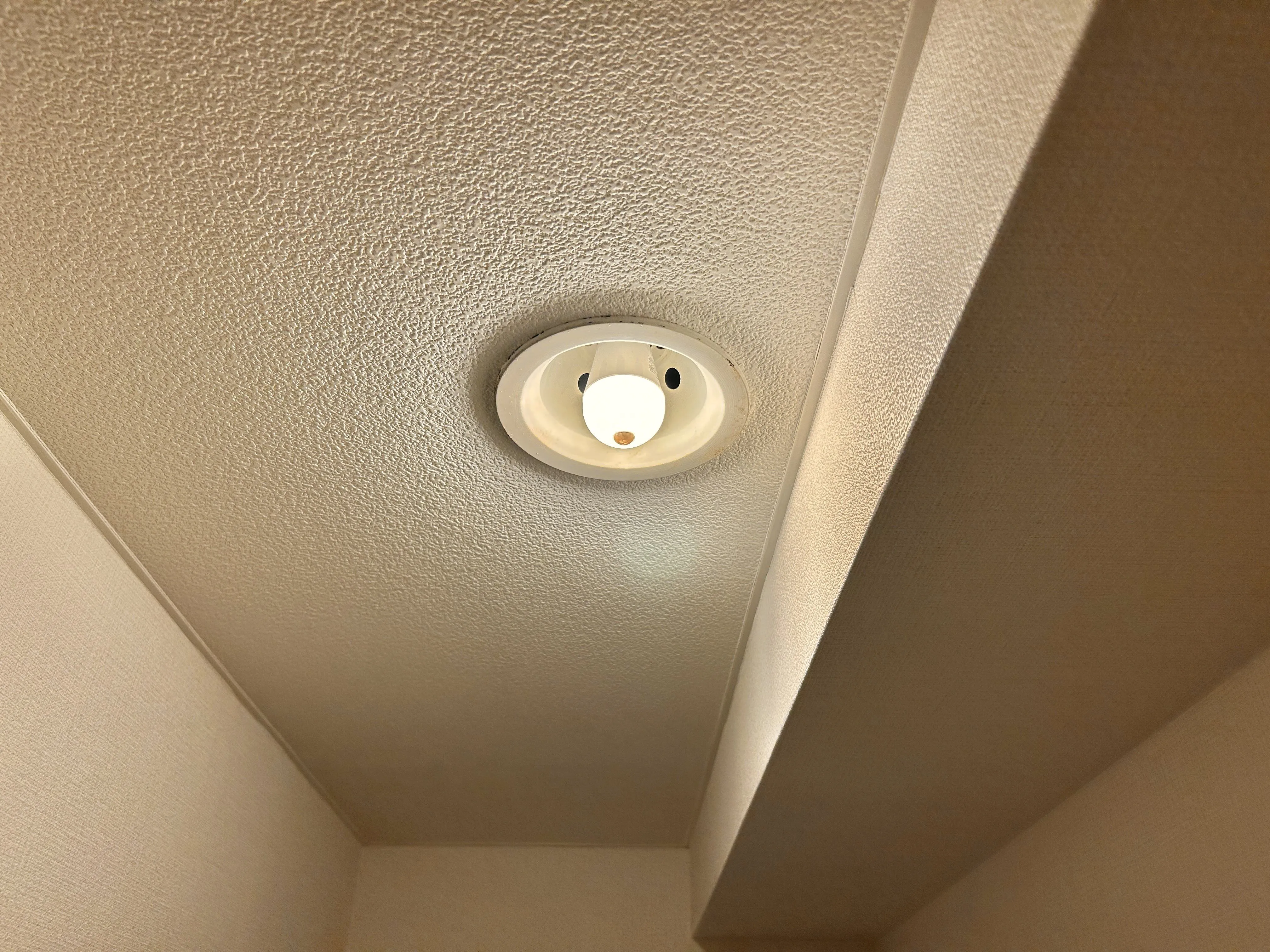 パナソニックの人感センサー付きLED電球を廊下のダウンライトに取り付けて点灯させた様子