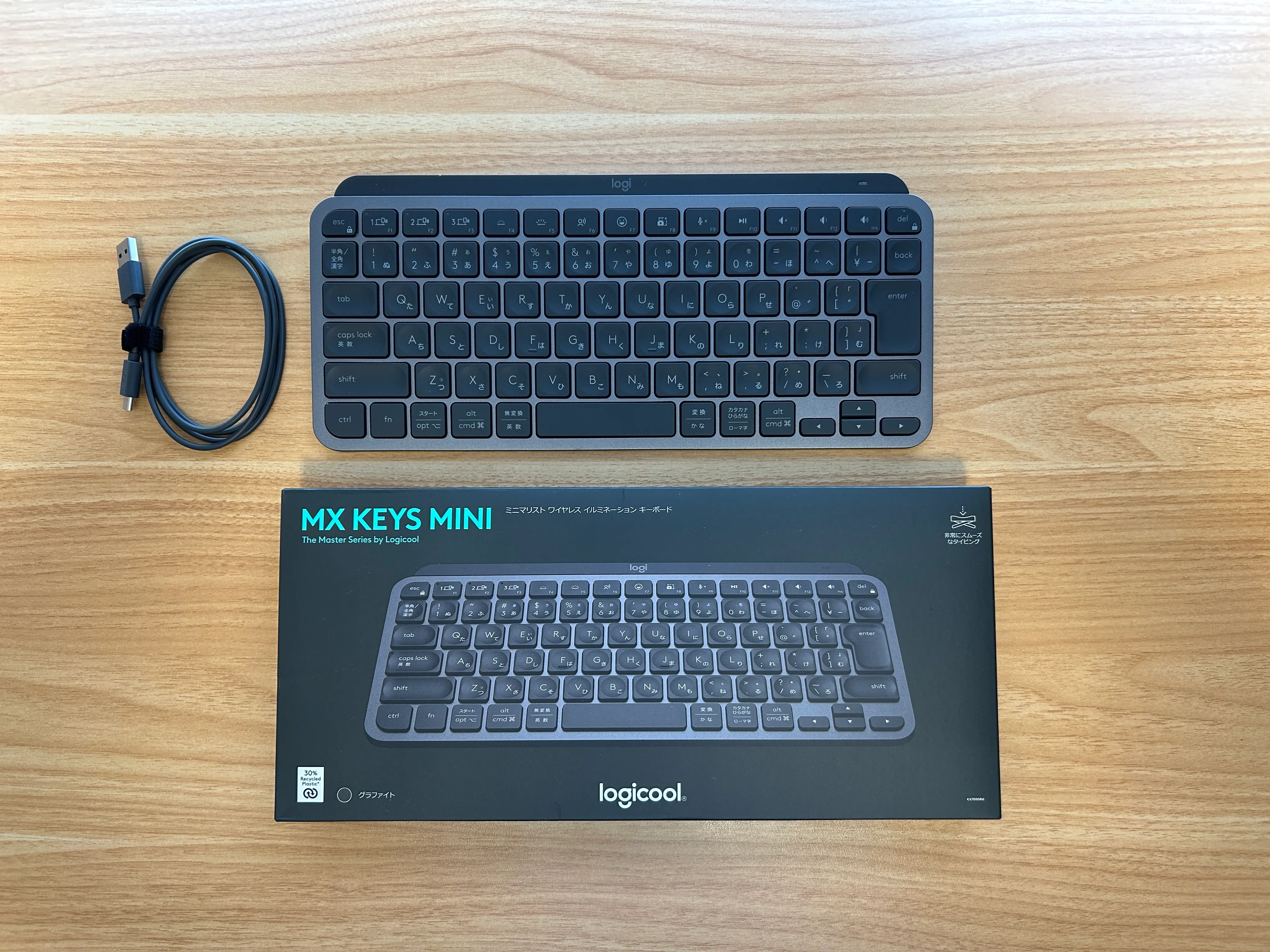 MX Keys Mini本体、付属の充電ケーブル、パッケージを木目の机に並べた写真
