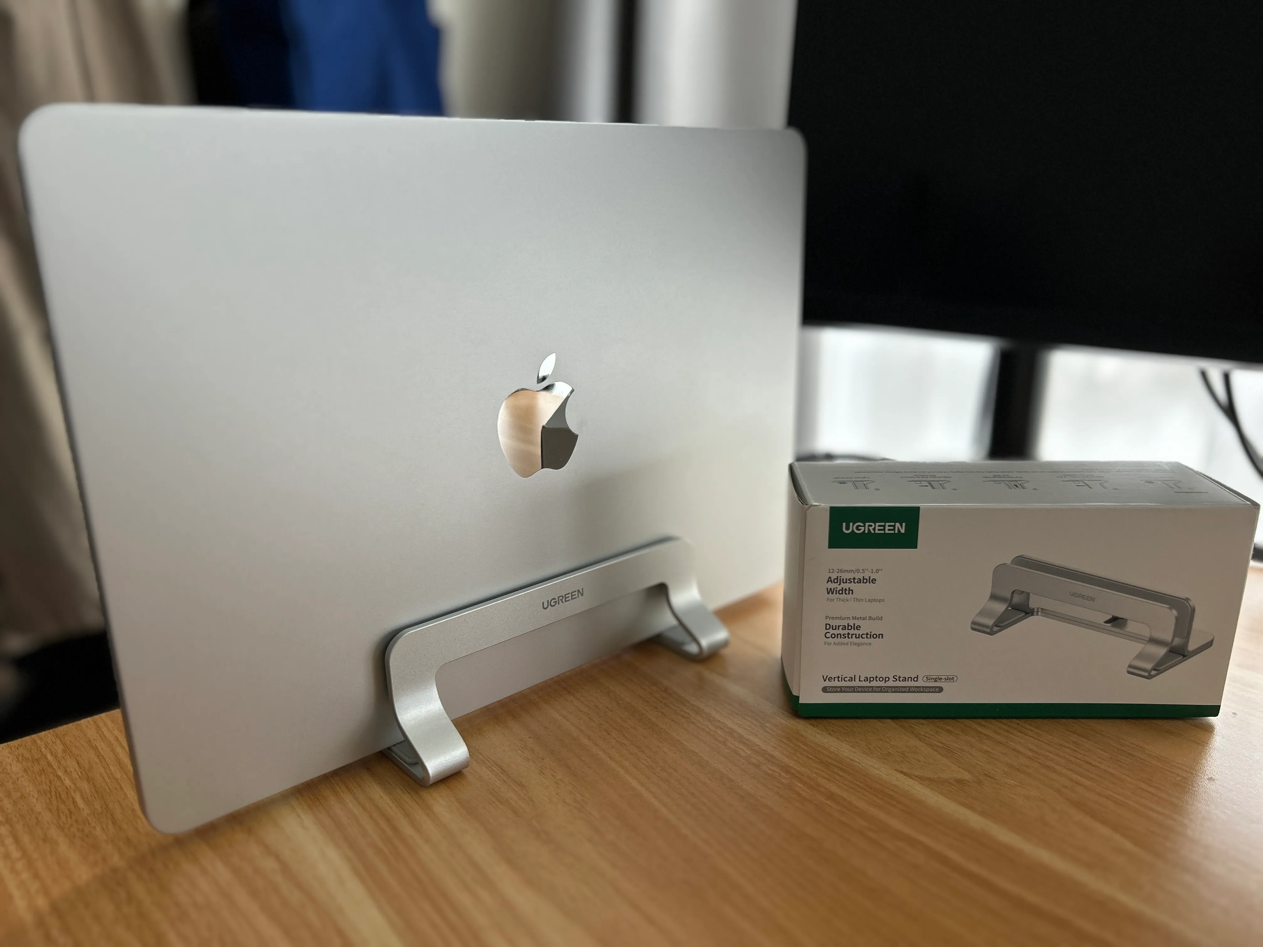 MacBookをUGREENの縦型スタンドに立て、パッケージも並べた机上の様子